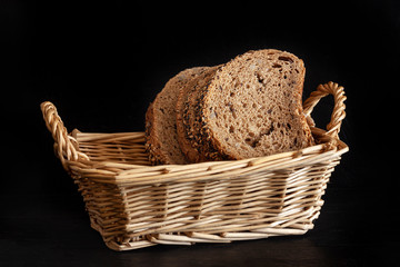 INTEGRAL BREAD ON WICKER BASKET AND BLACK BACKGROUND