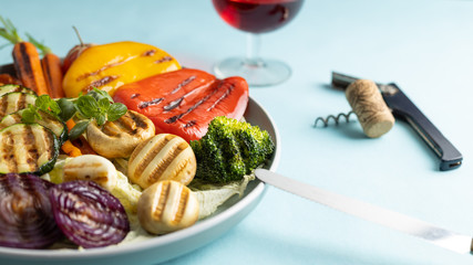 Fresh organic grilled vegetables bell pepper,mushrooms,broccoli,cauliflower,carrots seasoned with herbs on a round plate.