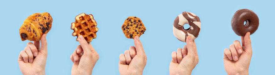Hands holding several sweet snacks on a blue background with copy space