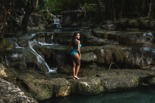 Young and sexy woman on the beautiful waterfall in the jungle