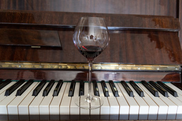 Glass with red wine on vintage piano keyboard