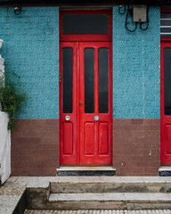 Obraz premium Red wooden door in old building with blue and brown tiles