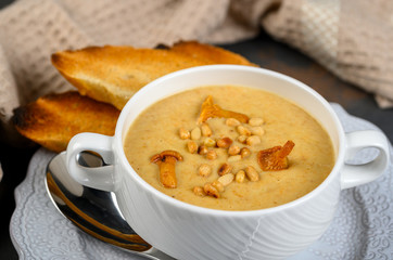 Mushroom, chanterelle cream soup with pine nuts and croutons on dark background