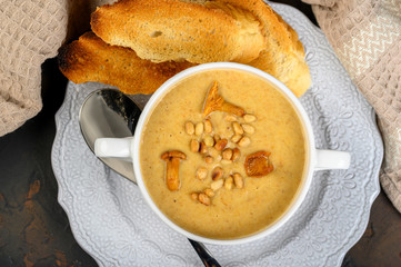 Mushroom, chanterelle cream soup with pine nuts and croutons on dark background
