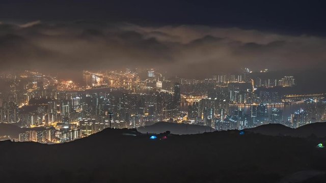 Night timelapse with grey transparent clouds flying on dark sky over city lights, cinematic background in Tai Mo Shan, Hong Kong