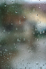 Window overlooking a rainy street. Gloomy evening weather with a view of the road. Drops on glass and bokeh from cars. Stock background for design