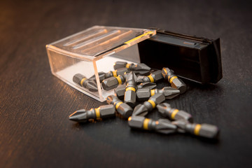 set of metal bits scattered on a black table screwdriver. all for repair.