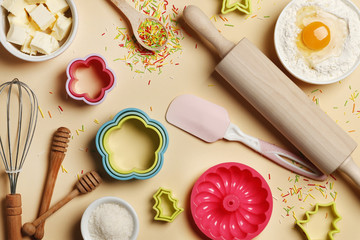 Fototapeta na wymiar Baking utensils and ingredients. Colorful silicone cooking utensils, rolling pin, sugar sprinkling, whisk with cookie mold on a colored background. Baking concept. Place for text. Easter concept.