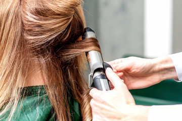 Fototapeta premium Hairdresser uses curling iron.