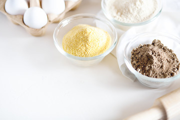 Various gluten free flour corn,sesame,oat,coconut in bowl on white background.Alternative to wheat flour for paleo diet.Healthy eating,dieting food concept.Horizontal orientation,top view,copy space