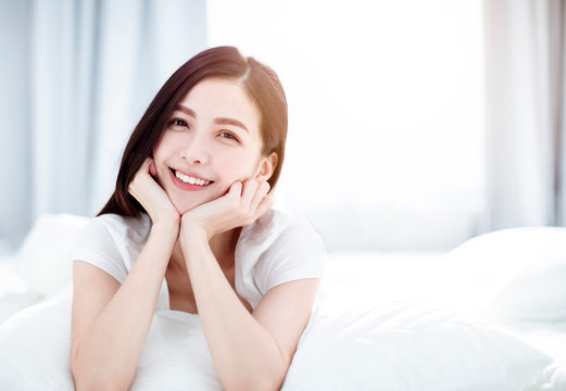 Young smiling woman lying in bed in  bedroom