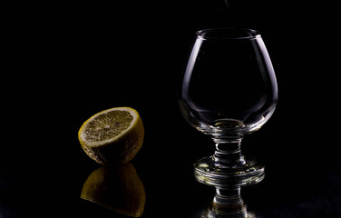 The silhouette of a glass on a black background in which liquid is poured from above with splashes