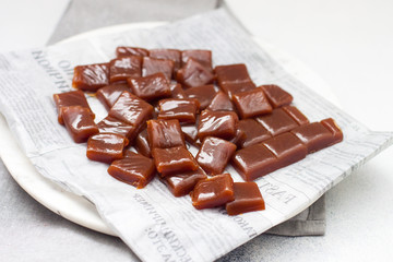 Salted caramel candies cut into square pieces, top view over grey baking paper