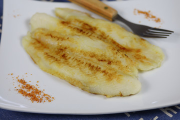 filet de tilapia en train de cuire dans une assiette