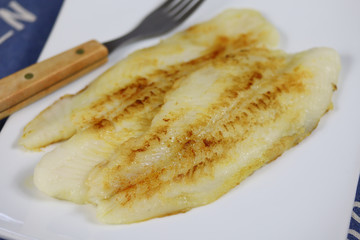 filet de tilapia en train de cuire dans une assiette