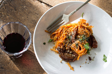 plato de pasta con tomate y vino en una mesa de madera