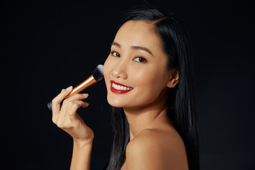 Obraz premium Beautiful Young Asian Woman using Soft Brush and Cosmetic on own face.