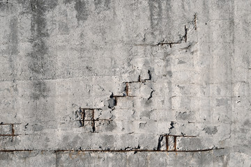 An old cracked concrete wall with rusty rebar