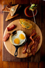 Breakfast, French style. Traditional classic Continental breakfast or brunch menu item served at bistro or diner. Crispy bacon, fried eggs, potatoes, bagel or flaky croissant w/ fresh jelly & butter.