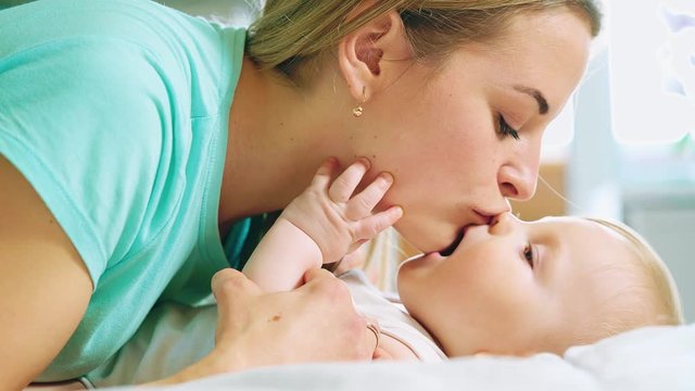 Happy mother and her baby. Mother kissing happy baby. Maternity concept