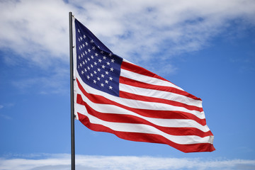 Fototapeta premium American flag on a nice summer day, symbol of Independence Day, July 4th, against background of dramatic blue sky