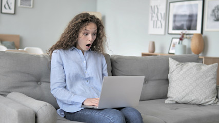 Shocked Curly Hair Woman working on Laptop, Sitting on Couch