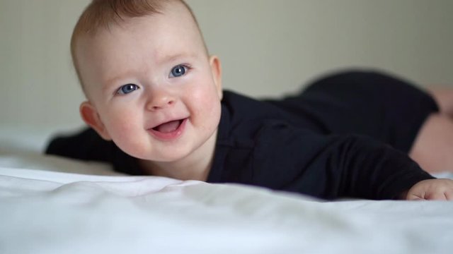 baby black clothes lying on paunch on white bed