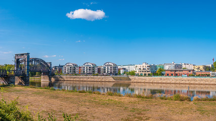 Fototapeta premium Cityscape of new buildings and old metal railway bridge in downtown of Magdeburg, Elbe riverbank, Germany