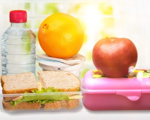 Lunch box with sandwiches, fruits and water on the desk