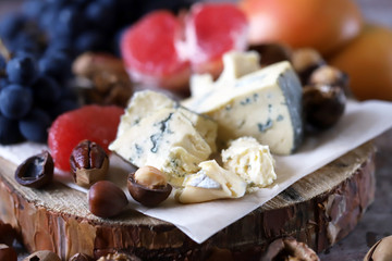 Selective focus. Healthy snack on a wooden tray. Cheese, nuts and fruits. Keto diet. Keto snack.