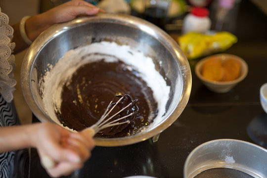 Woman hand mixing chocolate and flour by using a wire whisk, Homemade chocolate brownie cake.