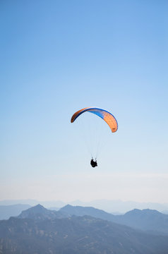 Paraca&iacute;das azul y naranja con paracaidista en el cielo deporte extremo