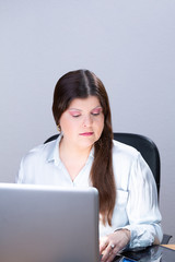 Business woman working on a computer in her office. She is serious and looking at the digital tablet screen. This is a studio portrait.