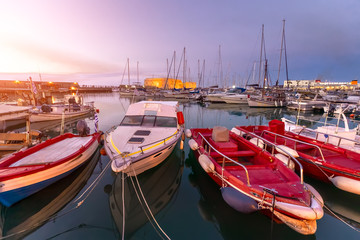 Fototapeta na wymiar Panoramic view of beautiful sunset in Koules Fortress (Rocca a Mare), Crete island. Yachts reflecting in the mirror of water near Venetian old harbor in Heraklion city. Amazing destination in Greece