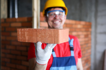 Smiling male builder showing fine quality brick material in camera