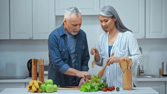 senior interracial couple cooking in kitchen