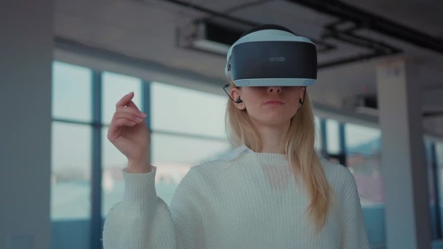 Close up woman using making gestures swipe when wearing virtual reality goggles empty building reaching technology looking entertainment gadget device tech game innovation portrait