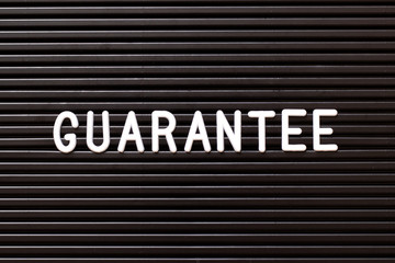 Black color felt letter board with white alphabet in word guarantee background