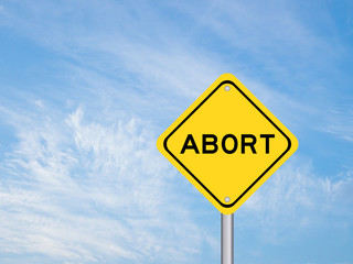Yellow transportation sign with word abort on blue sky background