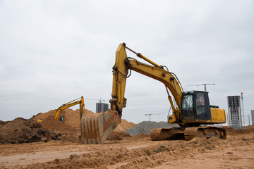 Excavators at earthworks on construction site. Backhoe loader digs a pit for the construction of...