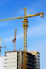 Concrete building under construction. Construction site. Two tower cranes near building.