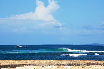 cruise boat riding on waves with seaview and shore near island Bali