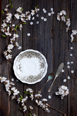 old dark rustic wooden table surface with white spring blossom flowers and antique silver dishware
