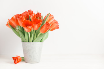 Romantic bouquet of bright red tulips in a grey vintage pot.