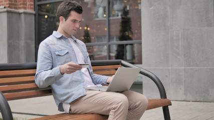 Online Shopping Failure for Young Man Sitting on Bench