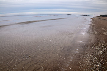 View of the sandy beach and the sea. Winter season. Cloudy, calm weather.