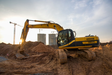 Excavator at earthworks on construction site. Backhoe loader digs a pit for the construction of the...