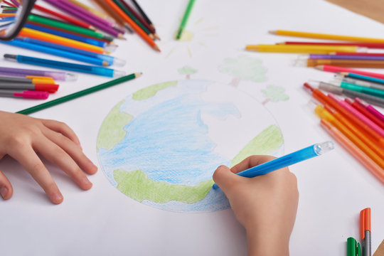 Child boy  draws  planet for earth day. Protection of enviroment, Mother Earth Day greeting and celebration. Save our planet! Concept of art learning and education, love earth , save world and unity