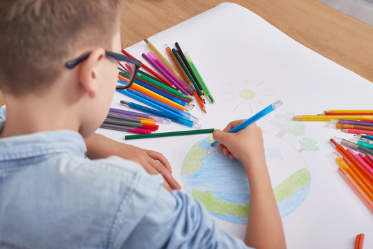 Child boy  draws  planet for earth day. Protection of enviroment, Mother Earth Day greeting and celebration. Save our planet! Concept of art learning and education, love earth , save world and unity
