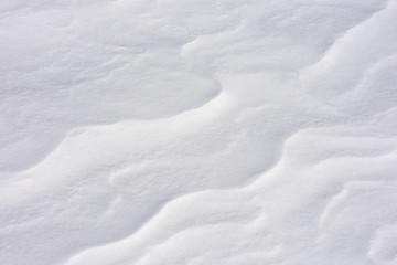 Snow close-up. Wavy texture. The Alpine slope is in the wind